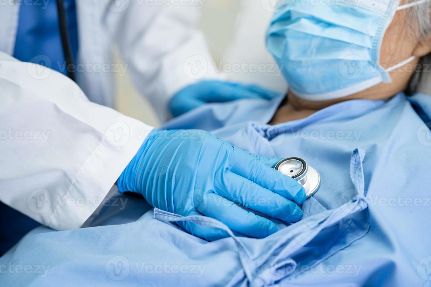 Doctor using stethoscope to checking Asian senior or elderly old lady woman patient wearing a face mask in hospital for protect infection Covid-19 Coronavirus. photo