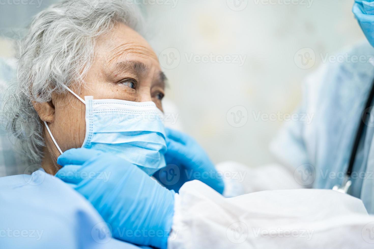 Doctor using stethoscope to checking Asian senior or elderly old lady woman patient wearing a face mask in hospital for protect infection Covid 19 Coronavirus. photo