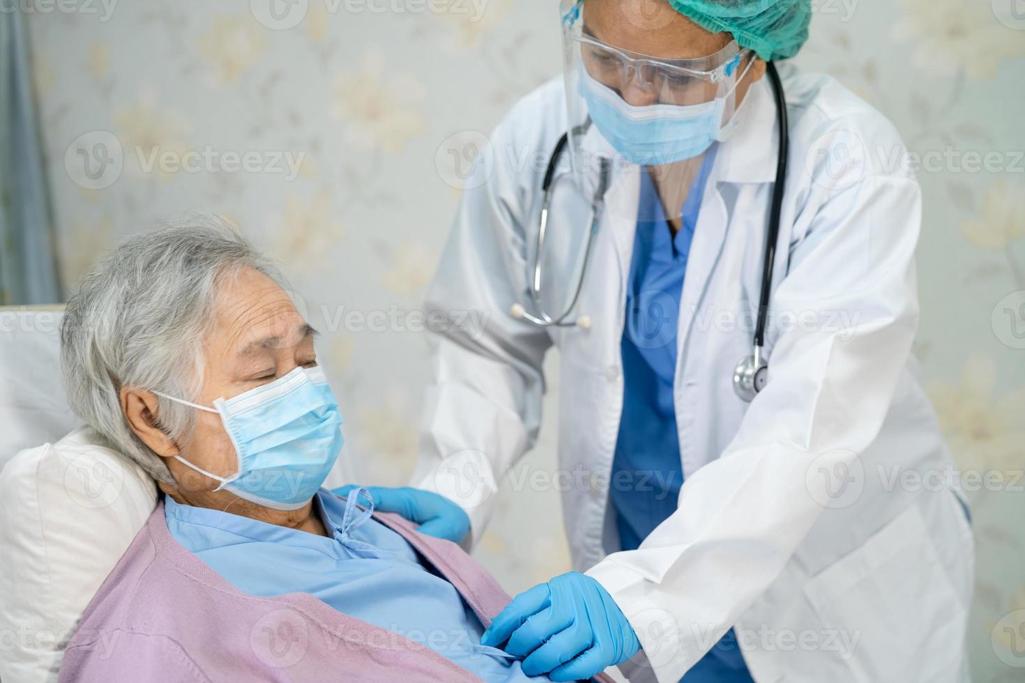 Doctor using stethoscope to checking Asian senior or elderly old lady woman patient wearing a face mask in hospital for protect infection Covid-19 Coronavirus. photo