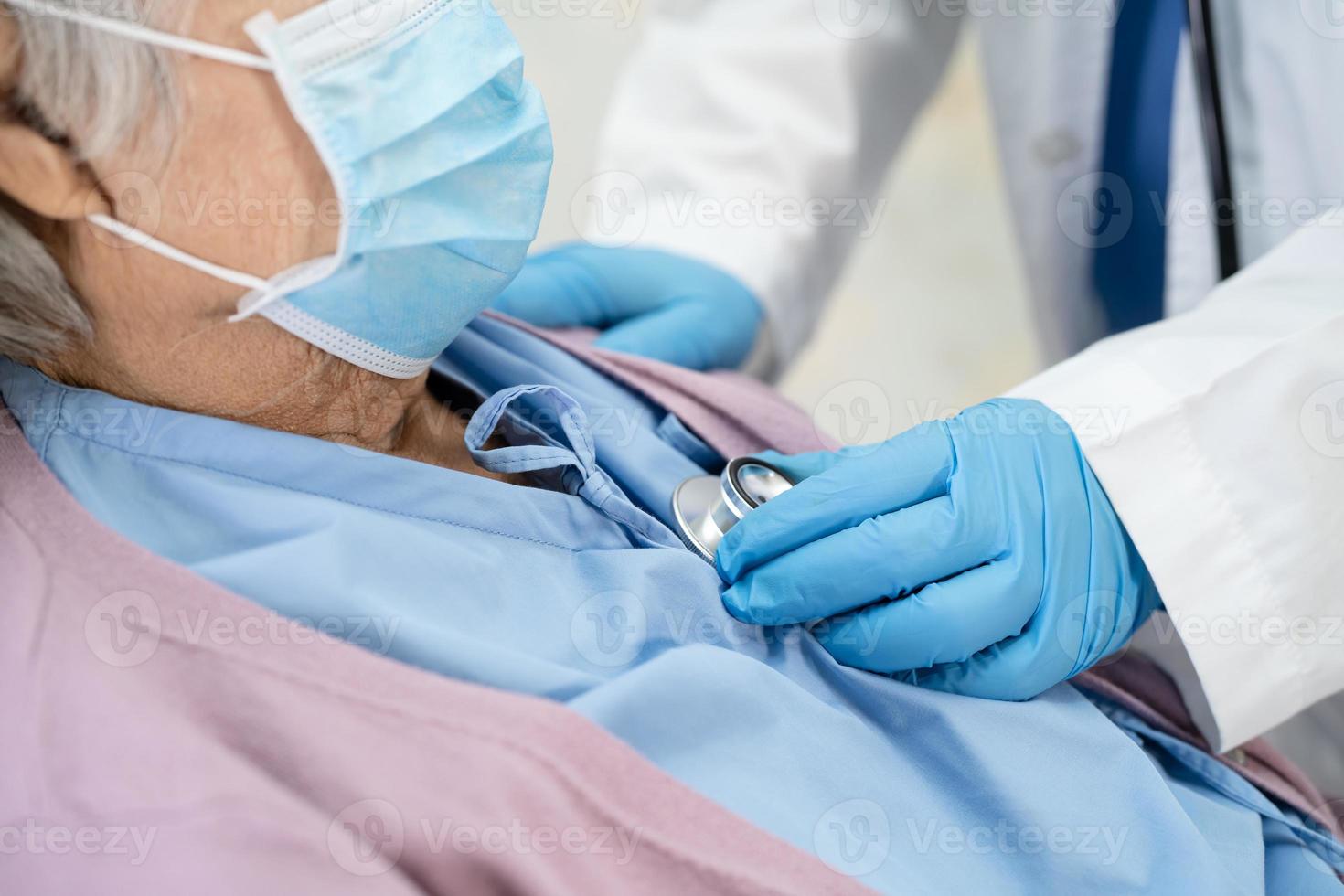 Doctor using stethoscope to checking Asian senior or elderly old lady woman patient wearing a face mask in hospital for protect infection Covid-19 Coronavirus. photo