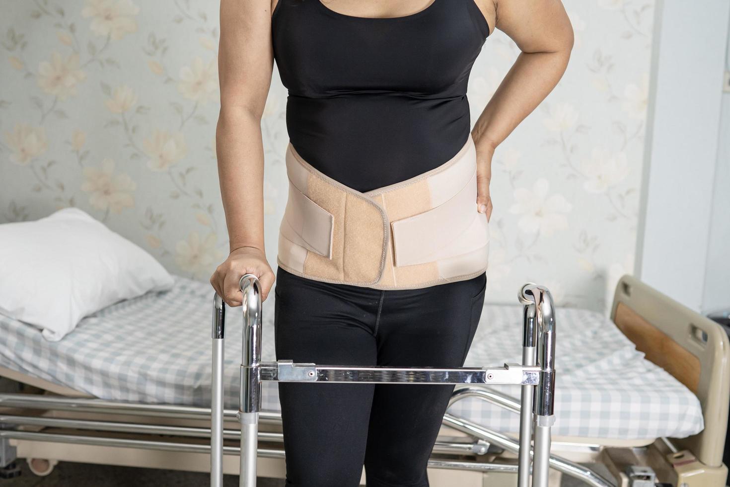 Asian lady patient wearing back pain support belt for orthopedic lumbar with walker. photo