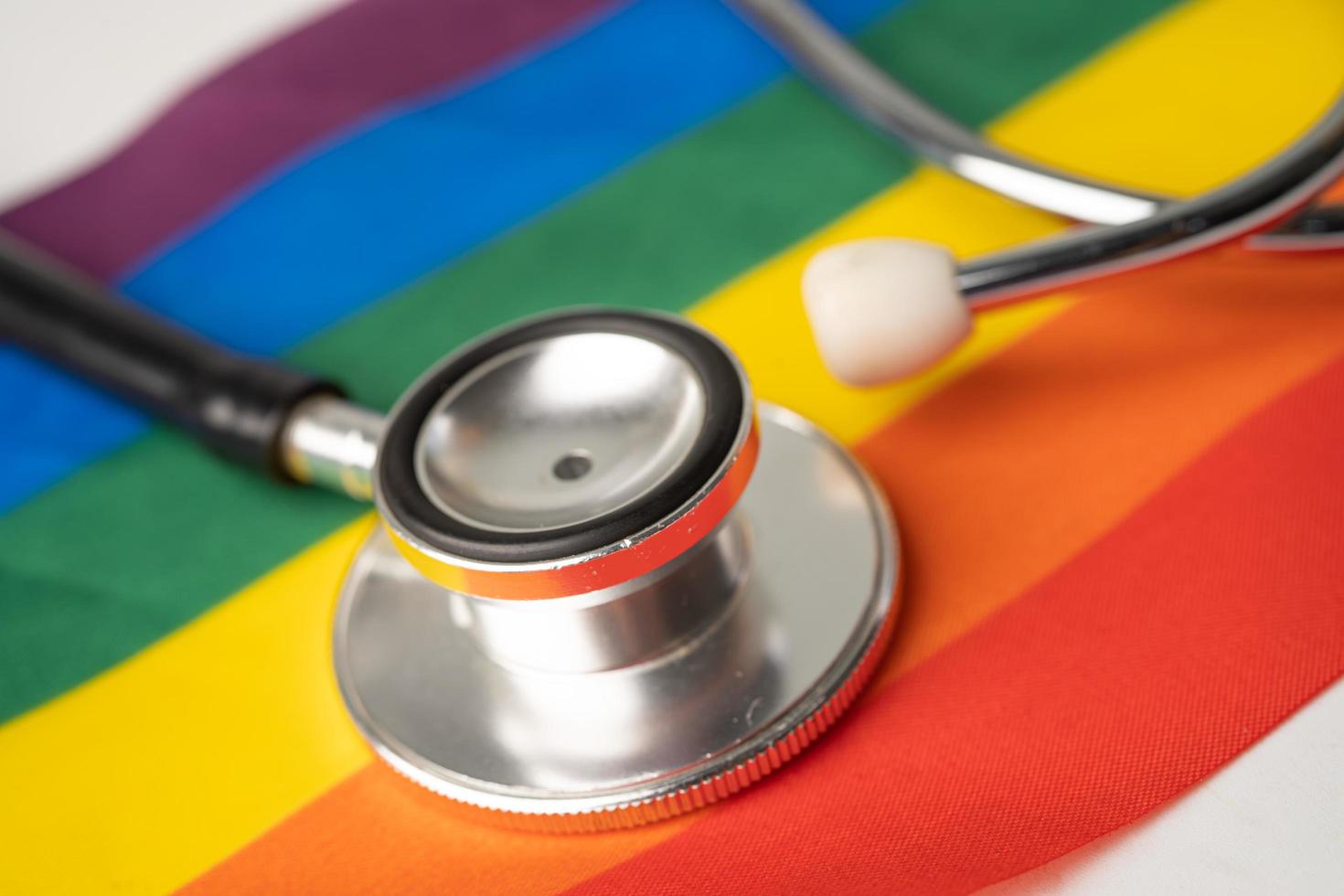 Black stethoscope on rainbow flag background, symbol of LGBT pride month celebrate annual in June social, symbol of gay, lesbian, bisexual, transgender, human rights and peace. photo