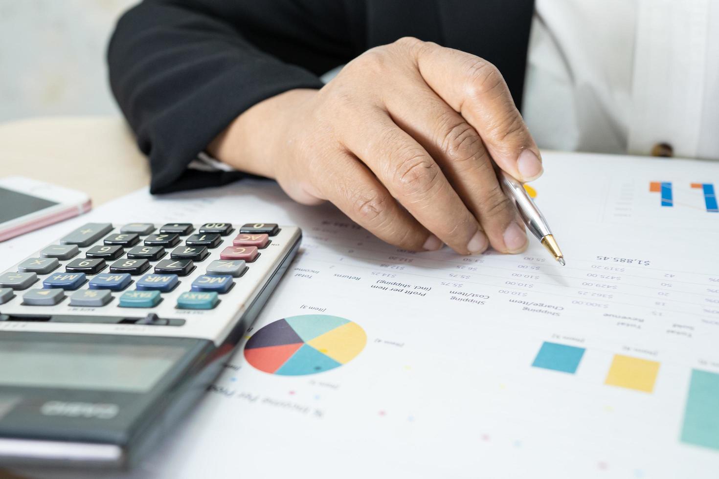 Asian accountant working and analyzing financial reports project accounting with chart graph and calculator in modern office, finance and business concept. photo