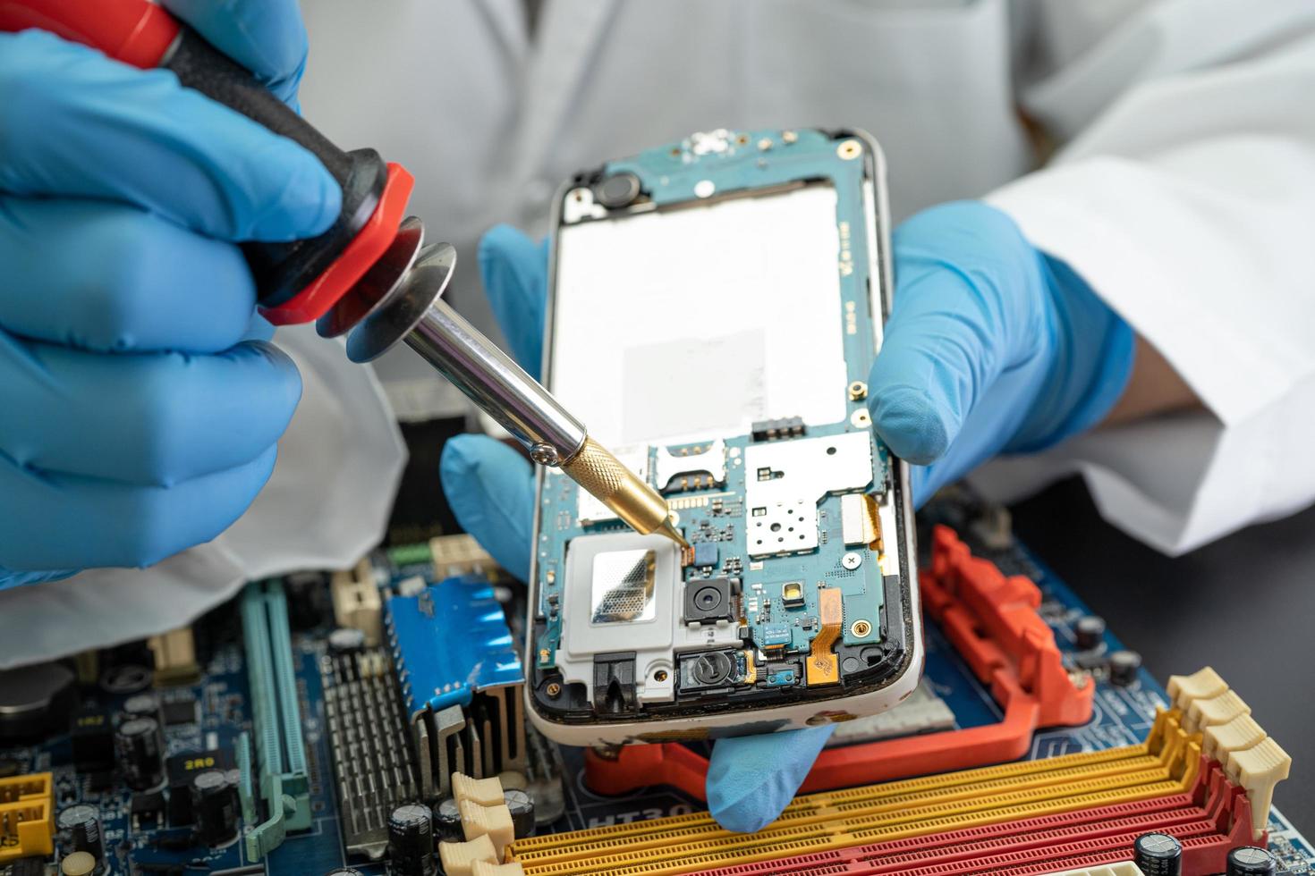 Technician repairing inside of mobile phone by soldering iron. Integrated Circuit. the concept of data, hardware, technology. photo