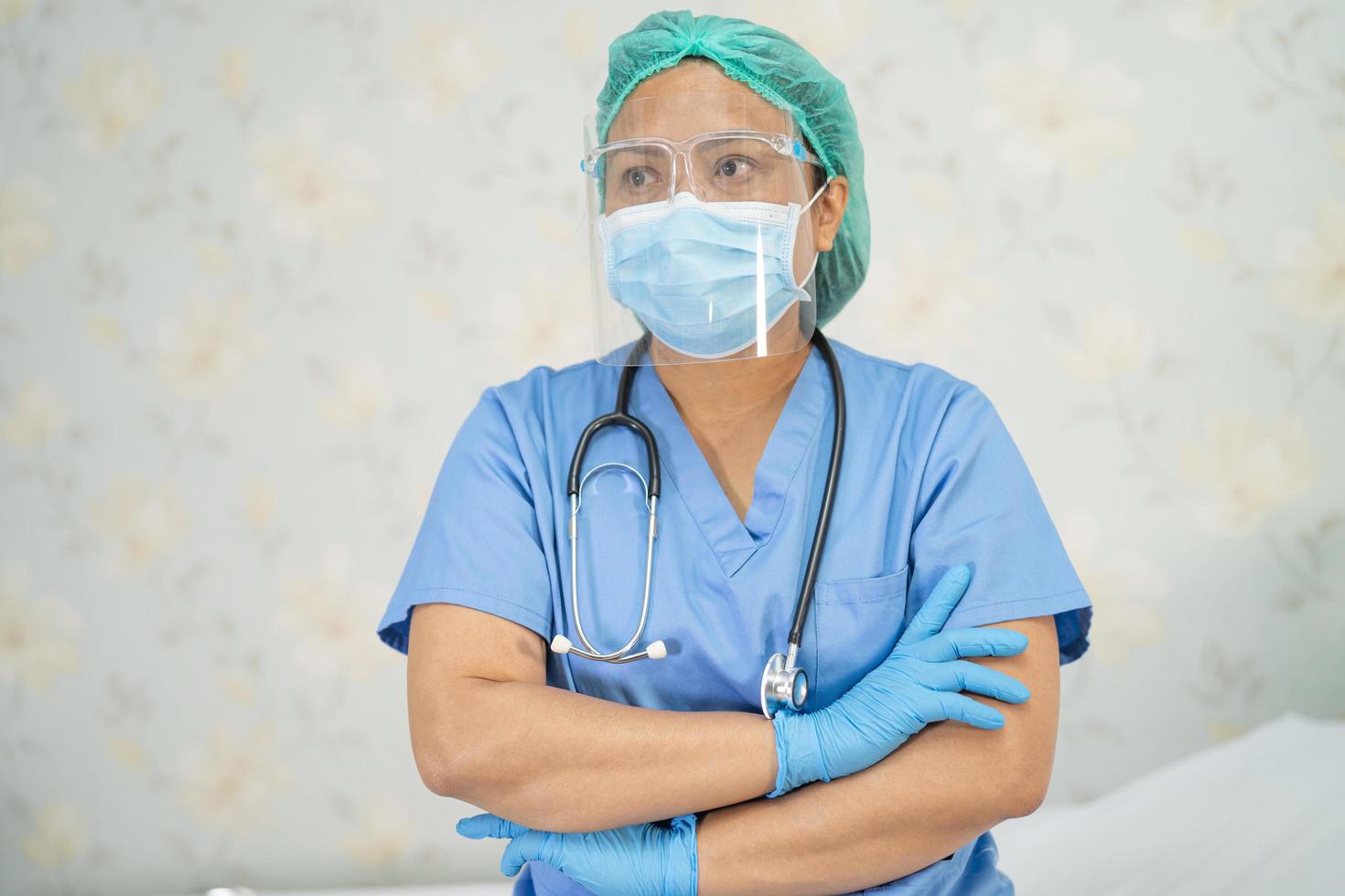 médico asiático con protector facial y traje de ppe nuevo normal para comprobar que el paciente protege la seguridad infección brote de coronavirus covid-19 en la sala de cuarentena del hospital de enfermería. foto