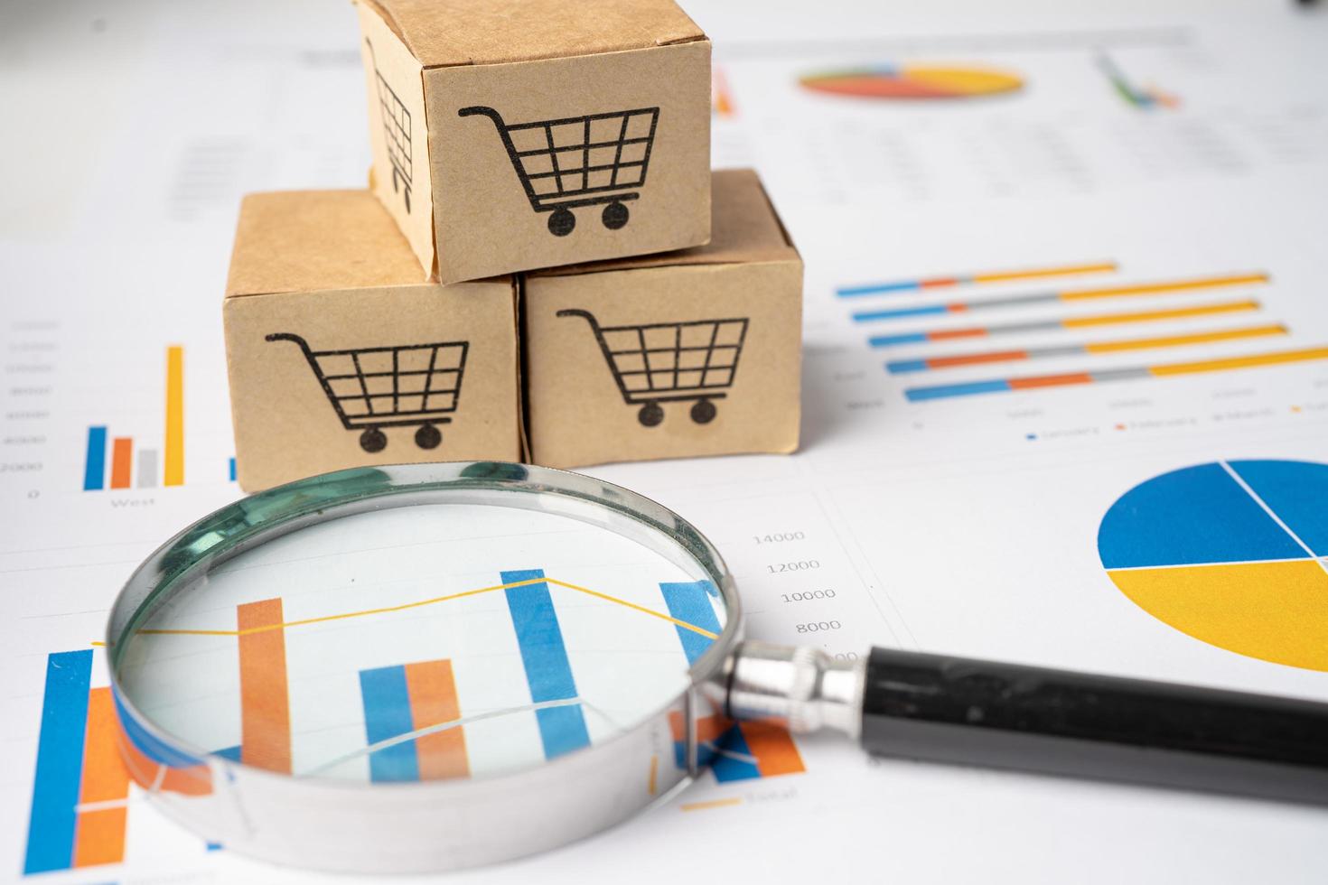 Shopping cart logo on box with magnifying glass on graph background. Banking Account, Investment Analytic research data economy, trading, Business import export transportation online company concept. photo
