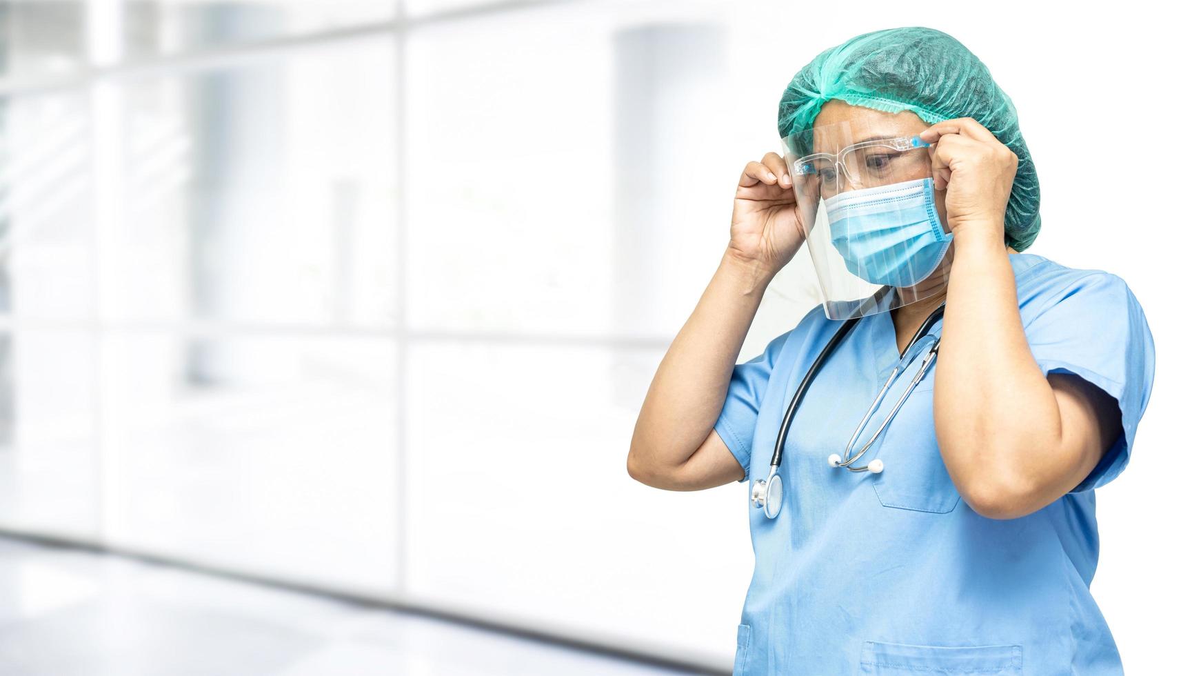 Asian doctor wearing face shield and PPE suit new normal to check patient protect safety infection Covid-19 Coronavirus outbreak at quarantine nursing hospital ward. photo