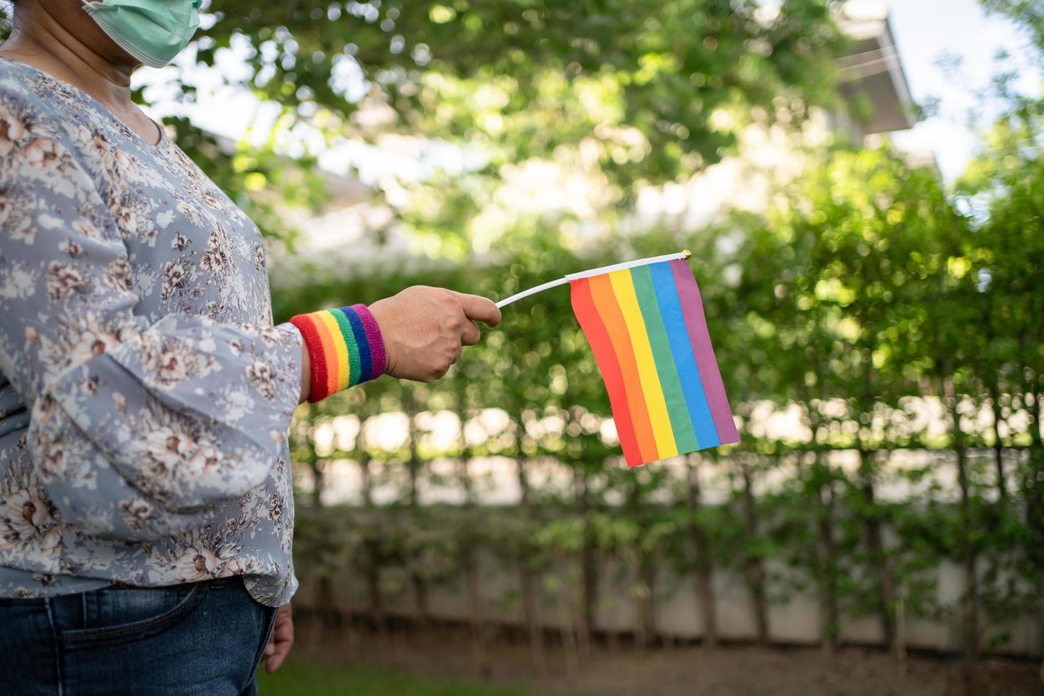 dama asiática sosteniendo la bandera del color del arco iris, símbolo del mes del orgullo lgbt celebra anualmente en junio las redes sociales de gays, lesbianas, bisexuales, transgénero, derechos humanos. foto