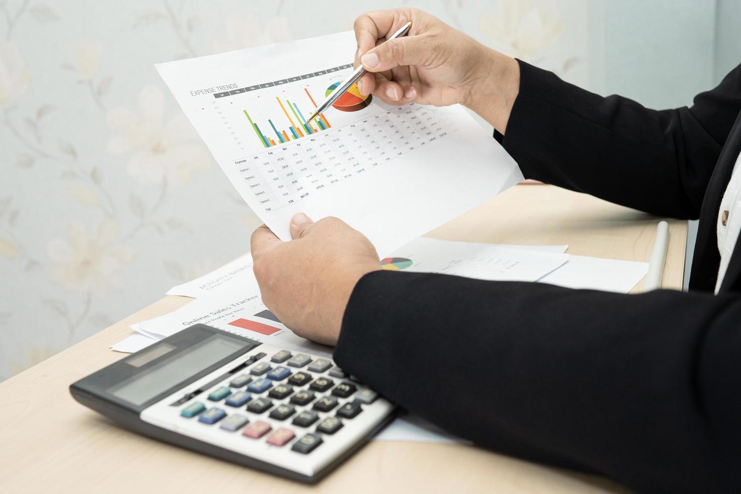 Asian accountant working and analyzing financial reports project accounting with chart graph and calculator in modern office, finance and business concept. photo