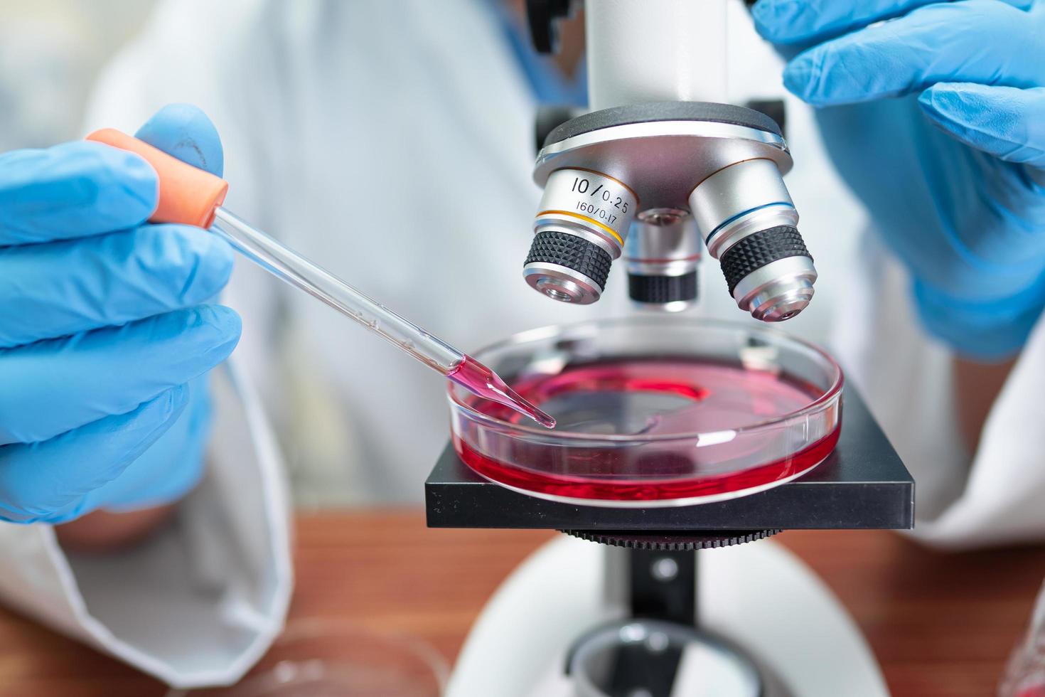 Asian scientist biochemist or microbiologist working research with a microscope in laboratory. For protect outbreak Coronavirus Covid19, bacteria and germs. photo