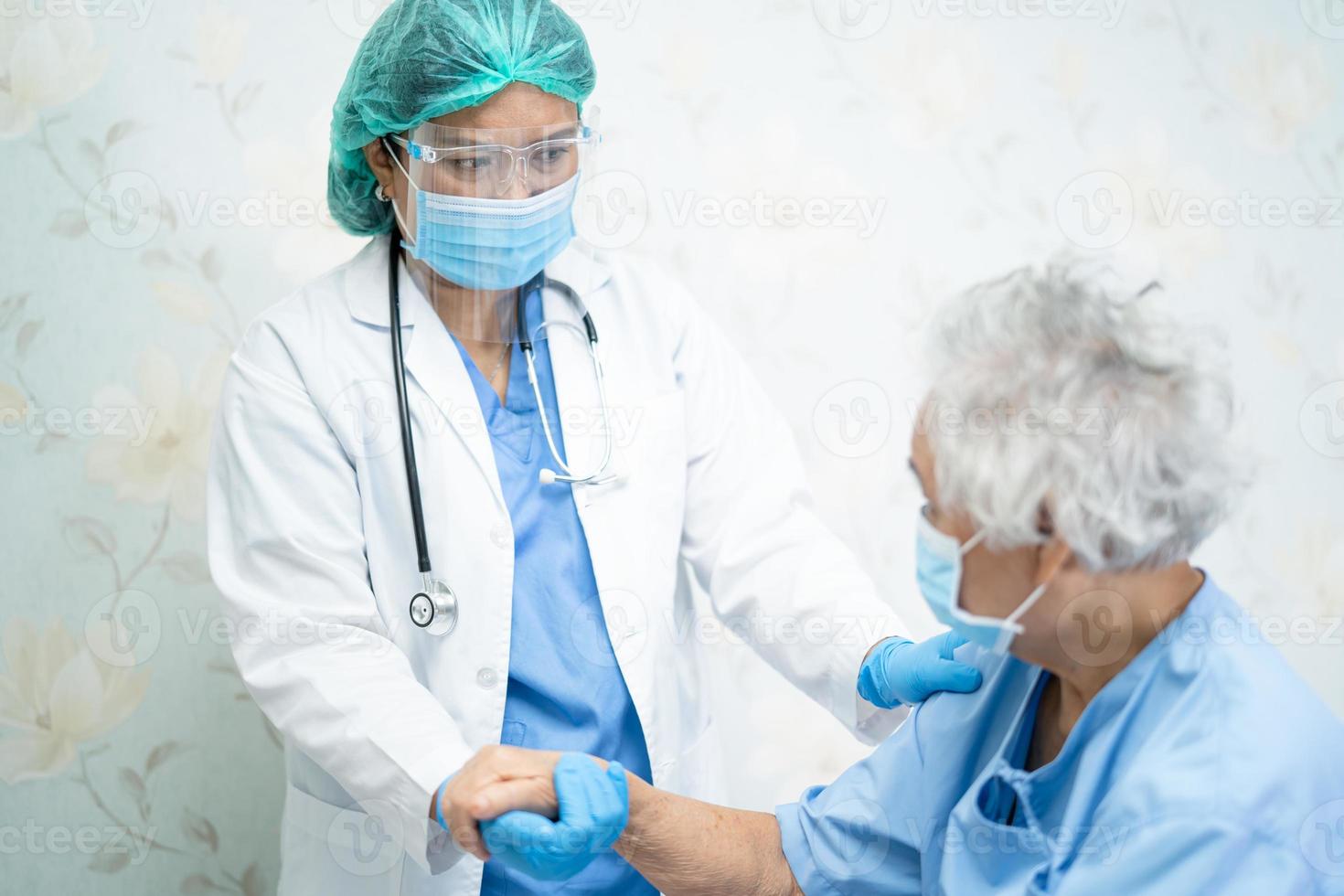 médico asiático con protector facial y traje de ppe nuevo normal para comprobar que el paciente protege la seguridad infección brote de coronavirus covid-19 en la sala de cuarentena del hospital de enfermería. foto