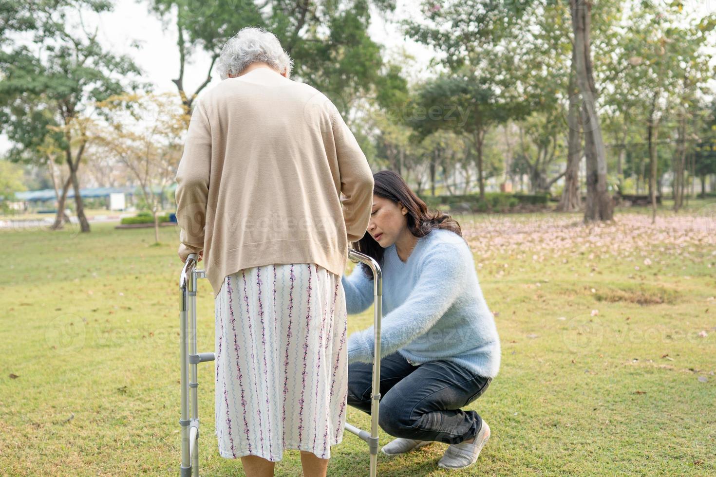 Help and care Asian senior or elderly old lady woman use walker with strong health while walking at park in happy fresh holiday. photo