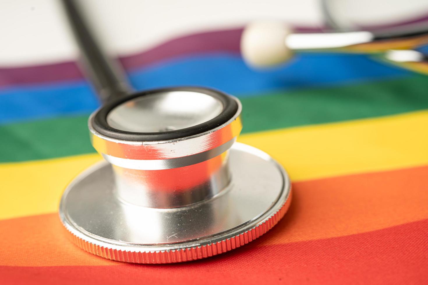 Black stethoscope on rainbow flag background, symbol of LGBT pride month celebrate annual in June social, symbol of gay, lesbian, bisexual, transgender, human rights and peace. photo