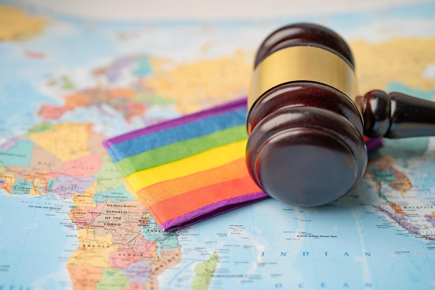 Bangkok, Thailand - December 1, 2020 LGBT rainbow flag with gavel for judge lawyer on world globe map. photo