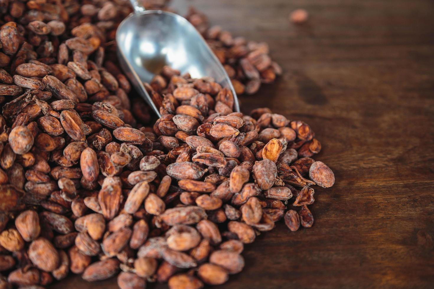 Granos de cacao crudo en una mesa de madera foto