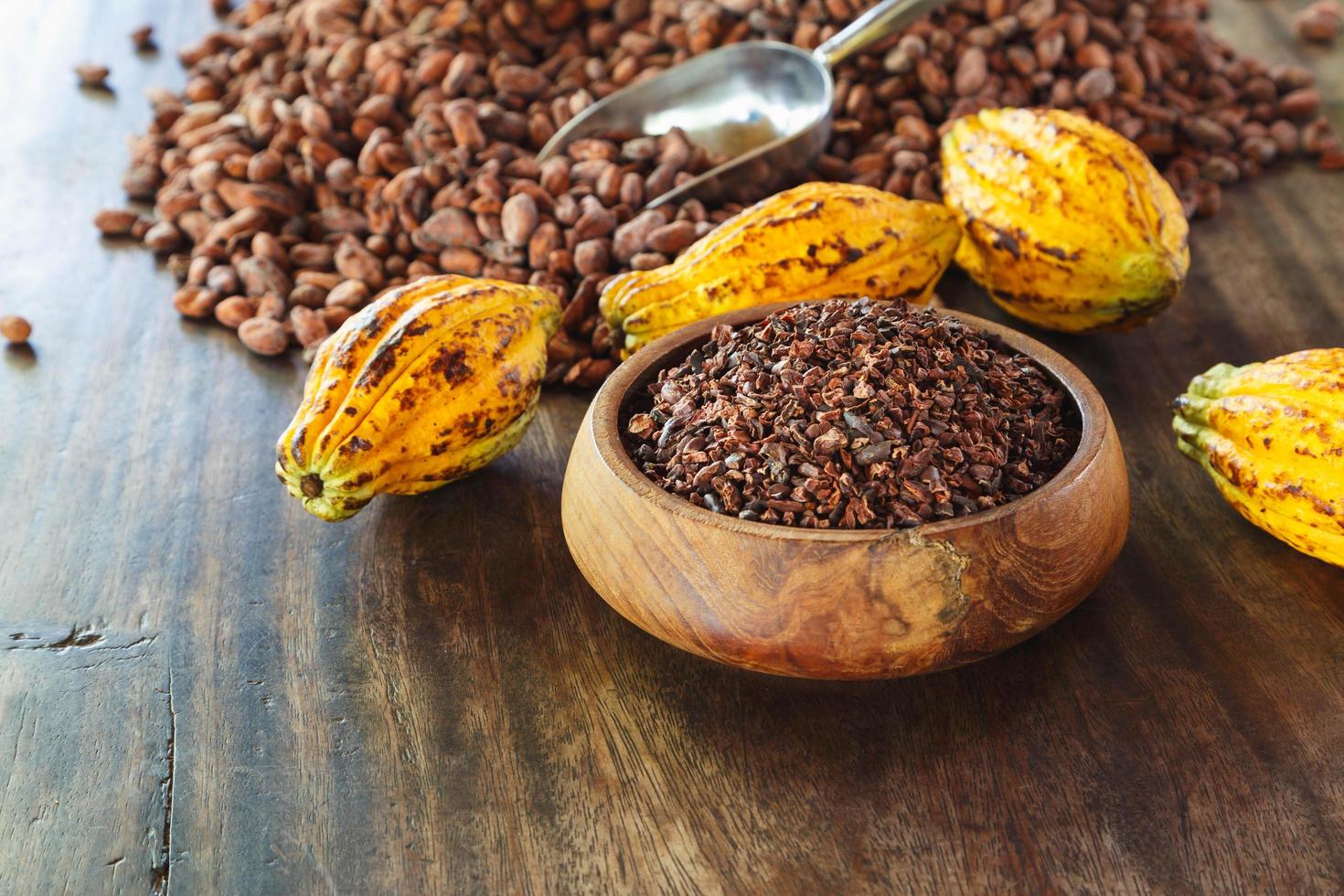 Nibs de cacao y frutos de cacao en la mesa de madera foto
