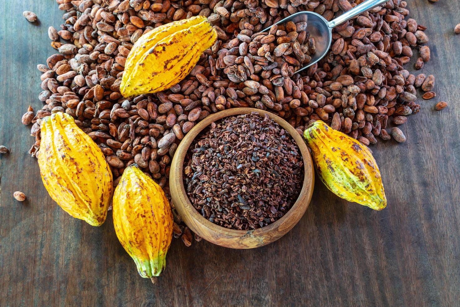 Nibs de cacao y frutos de cacao en la mesa de madera foto