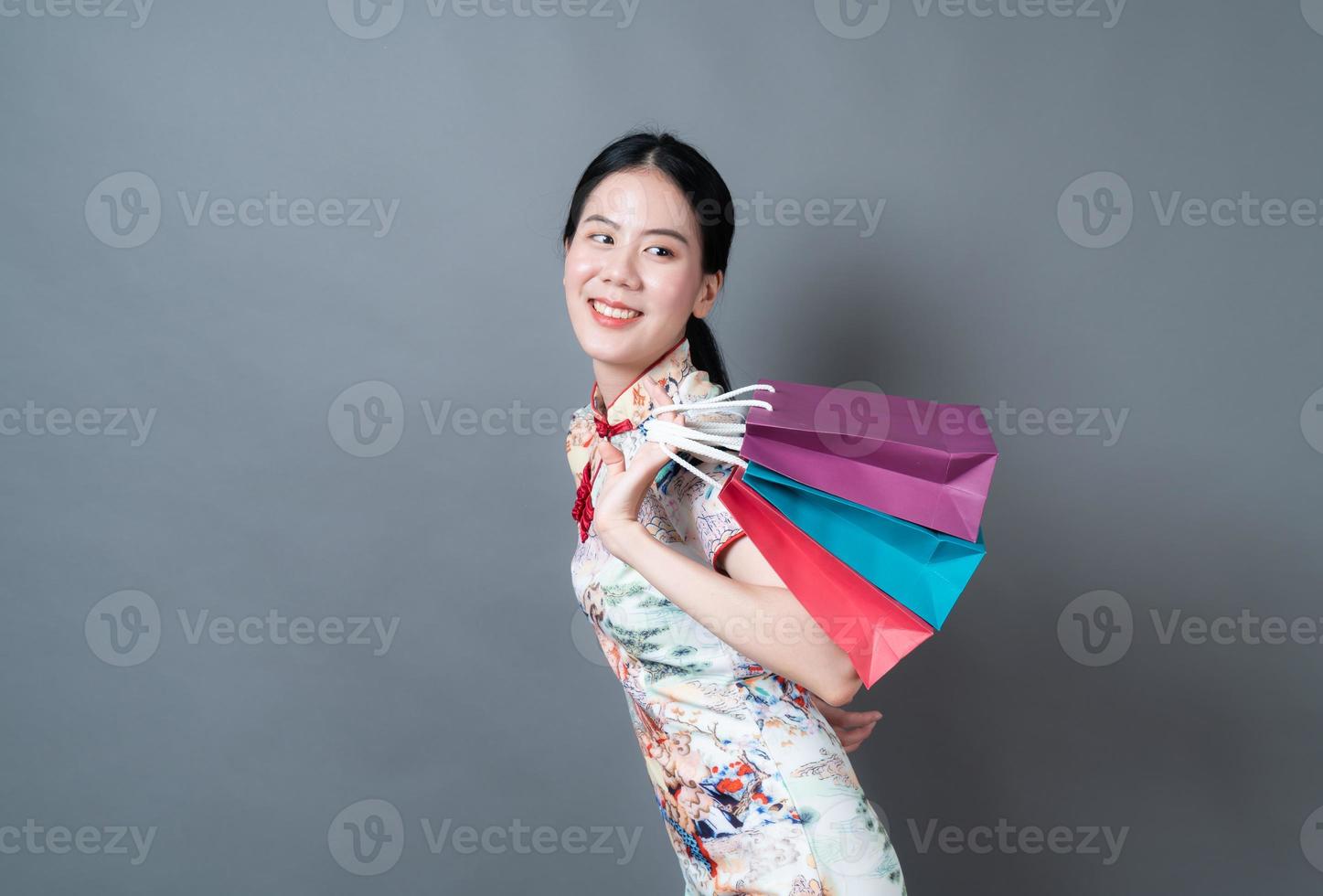 Mujer asiática vistiendo traje tradicional chino con mano sujetando la bolsa de compras foto