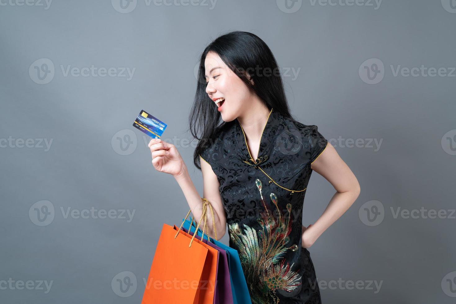 Mujer asiática vistiendo traje tradicional chino con bolsa de compras y tarjeta de crédito foto