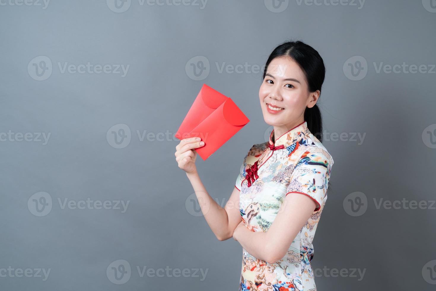 Mujer asiática vistiendo traje tradicional chino con sobre rojo o paquete rojo foto