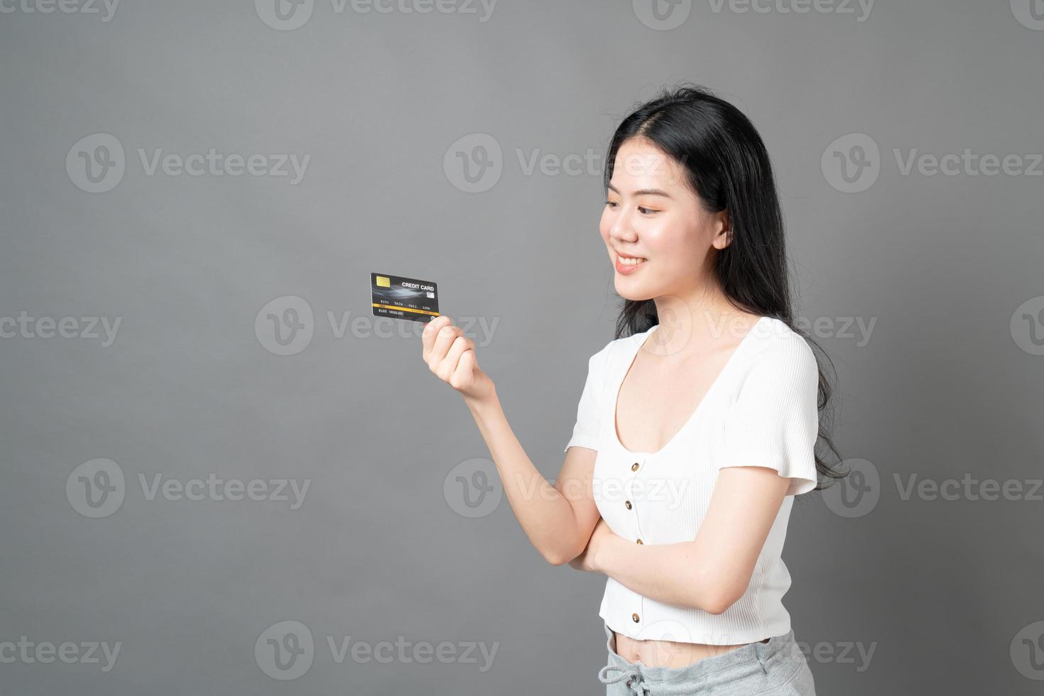 Mujer asiática con cara feliz y presentando tarjeta de crédito en mano mostrando confianza y seguridad para realizar el pago foto