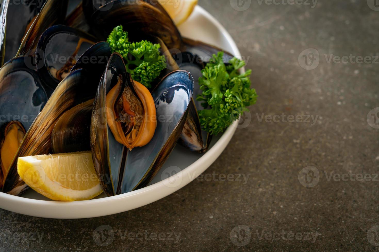 mejillones con hierbas en un bol con limón foto