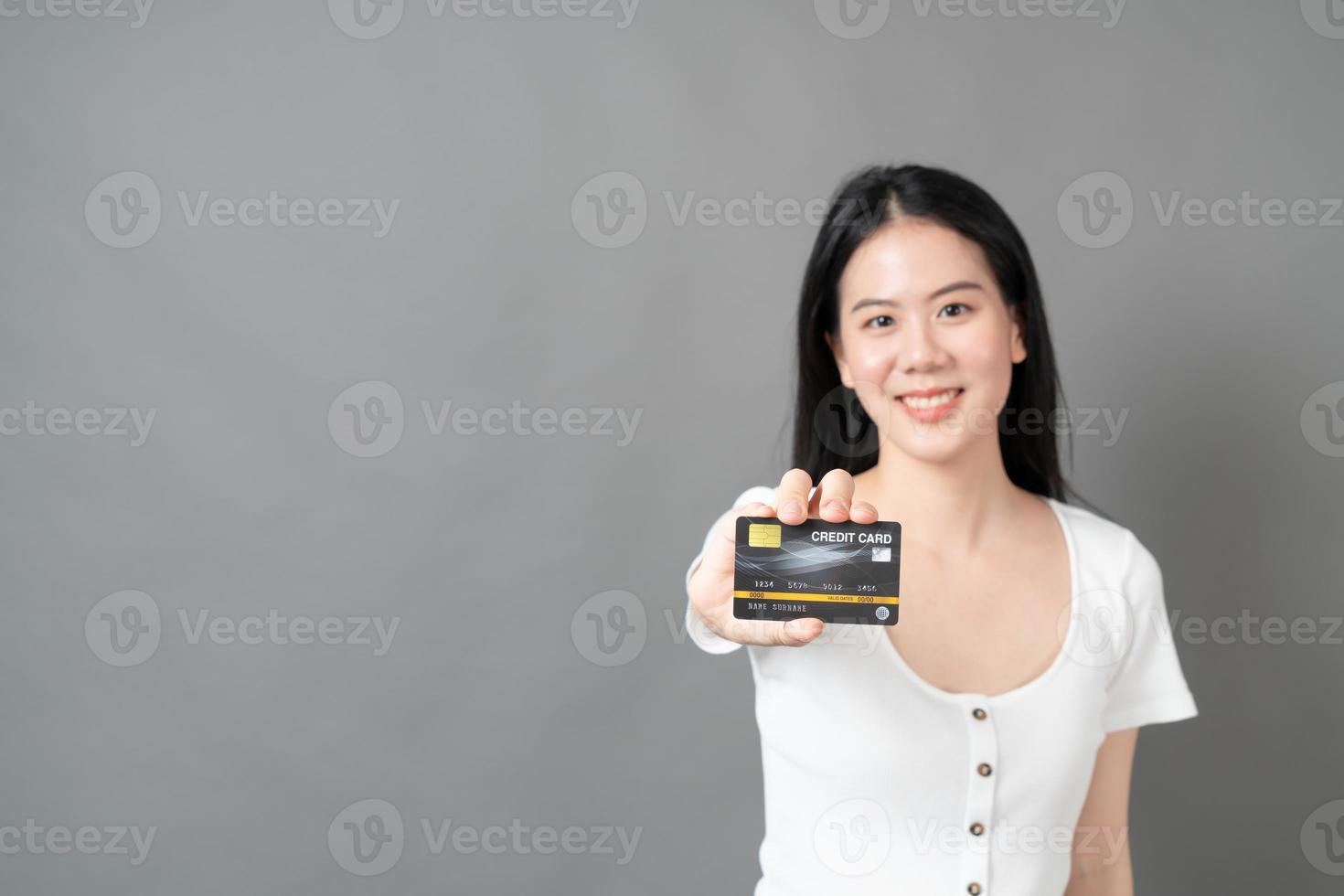 Mujer asiática con cara feliz y presentando tarjeta de crédito en mano mostrando confianza y seguridad para realizar el pago foto