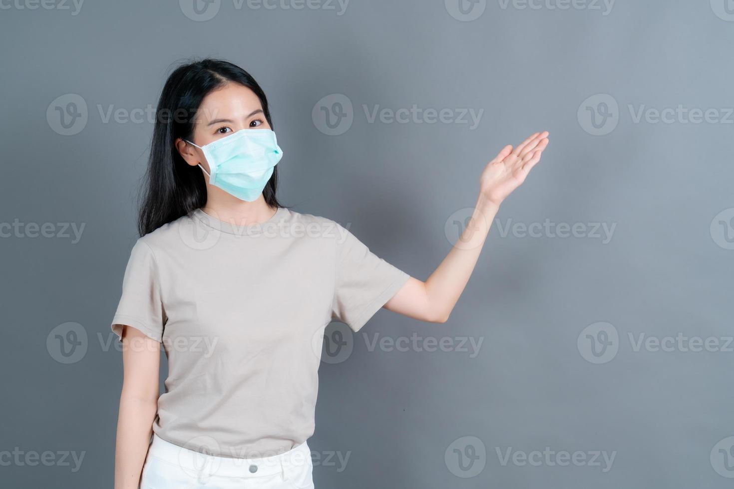 Mujer asiática con mascarilla médica protege el polvo del filtro pm2.5 anti-contaminación, anti-smog y covid-19 con presentación de la mano foto