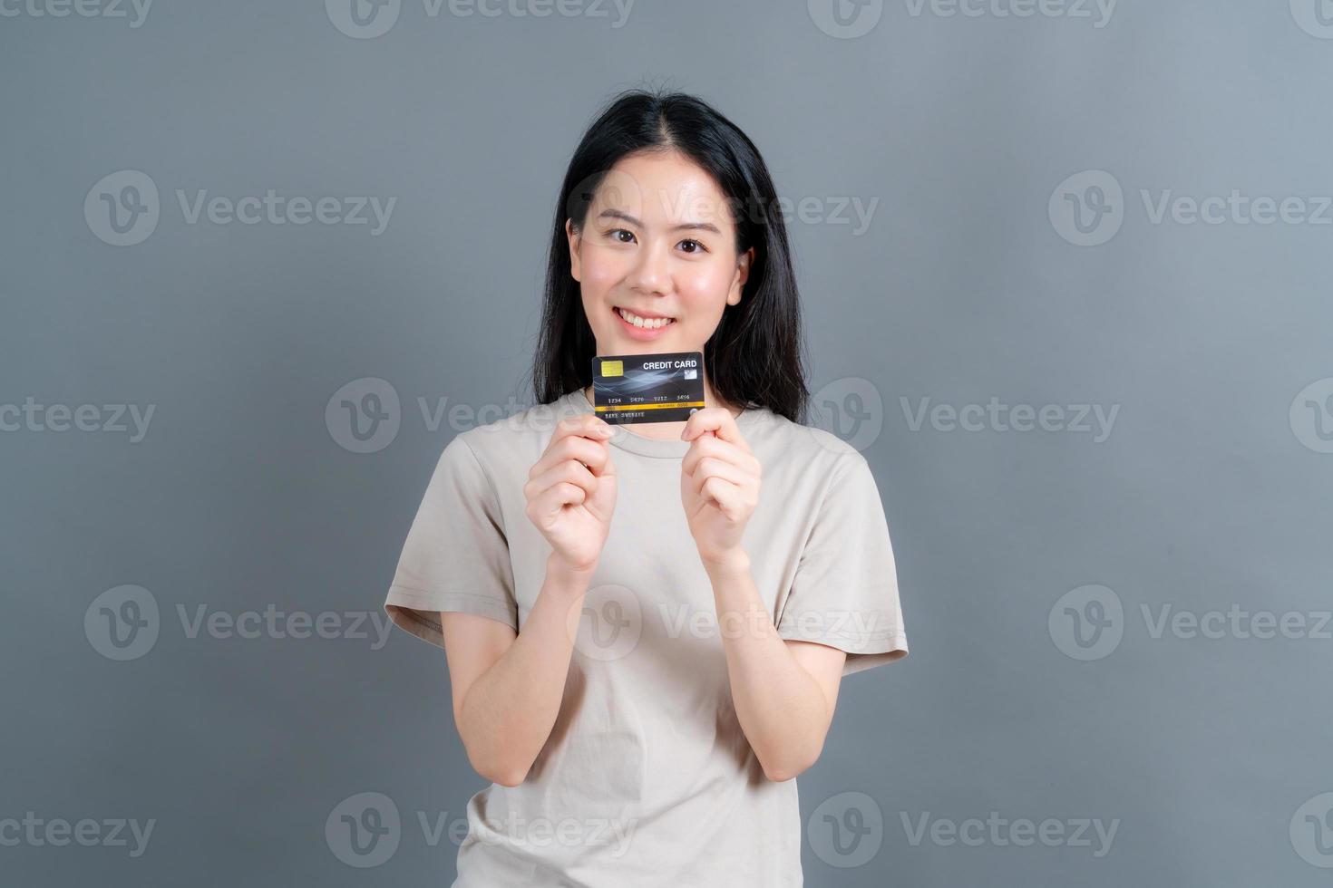 Portrait of a lovely young Asian woman showing credit card photo