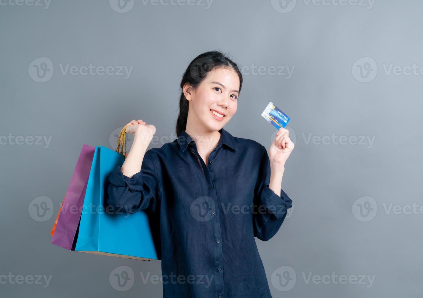 Hermosa mujer asiática con bolsas de la compra y mostrando tarjeta de crédito foto