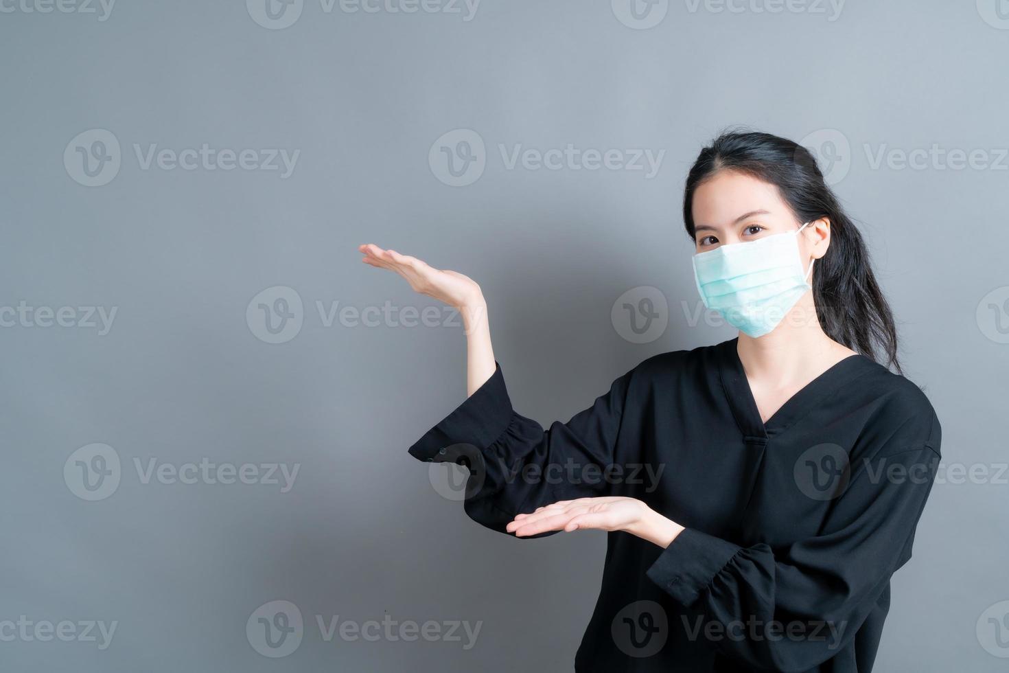 Asian woman wearing medical face mask protects filter dust pm2.5 anti-pollution, anti-smog, and COVID-19 with hand presenting photo
