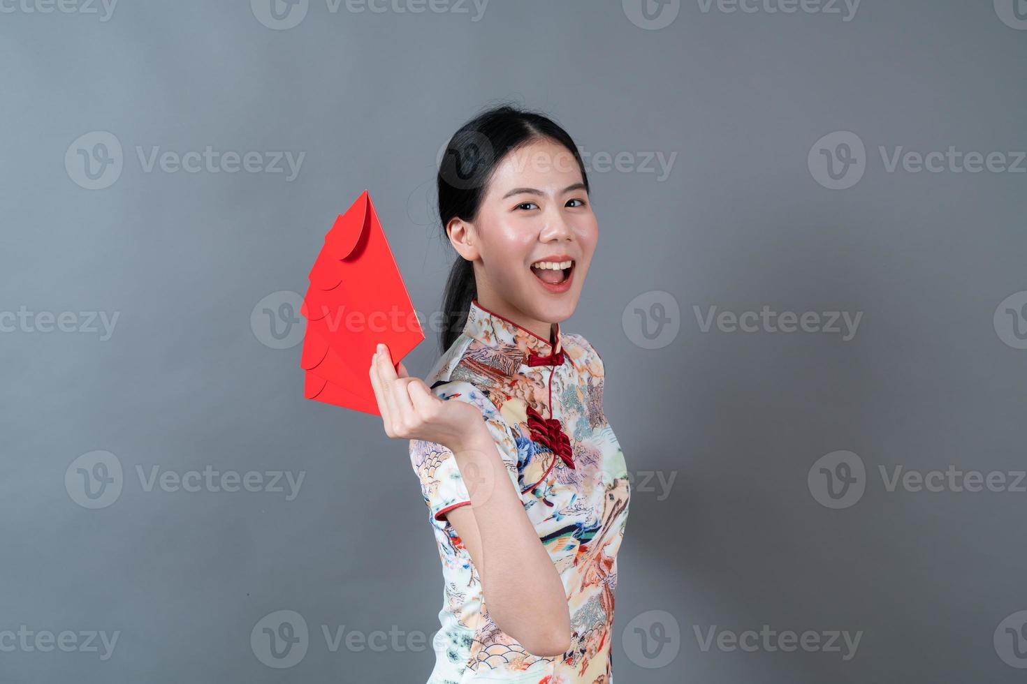 Mujer asiática vistiendo traje tradicional chino con sobre rojo o paquete rojo foto