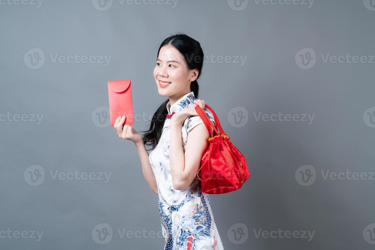 Mujer asiática vistiendo traje tradicional chino con sobre rojo o paquete rojo foto