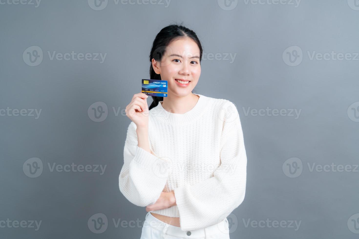 Portrait of a lovely young Asian woman in sweater showing credit card with copy space photo