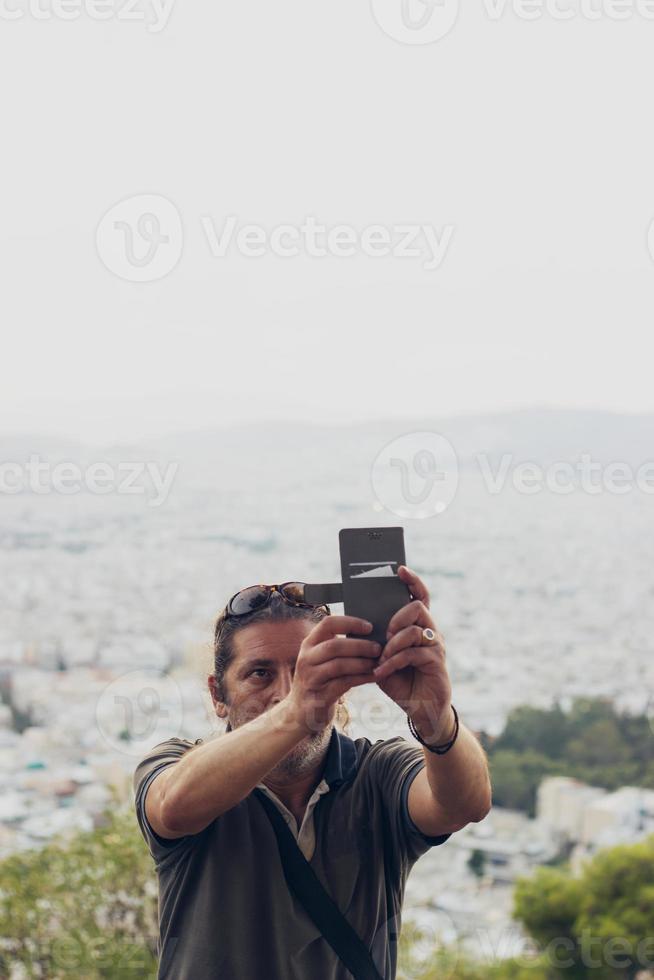 Man is taking a selfie on the hill, cityscape is in the background photo