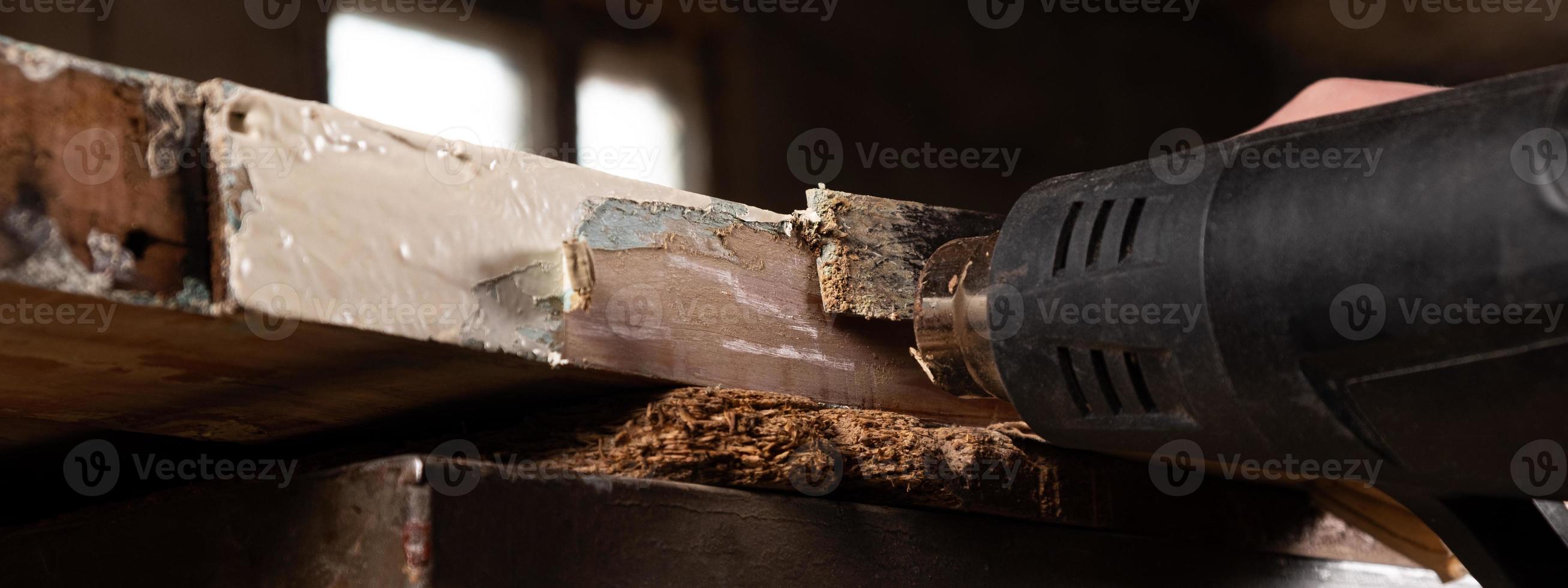 Quitar la pintura vieja de las puertas de madera antiguas con una espátula y una pistola de calor, restaurando el panorama de superficies de madera antiguas foto