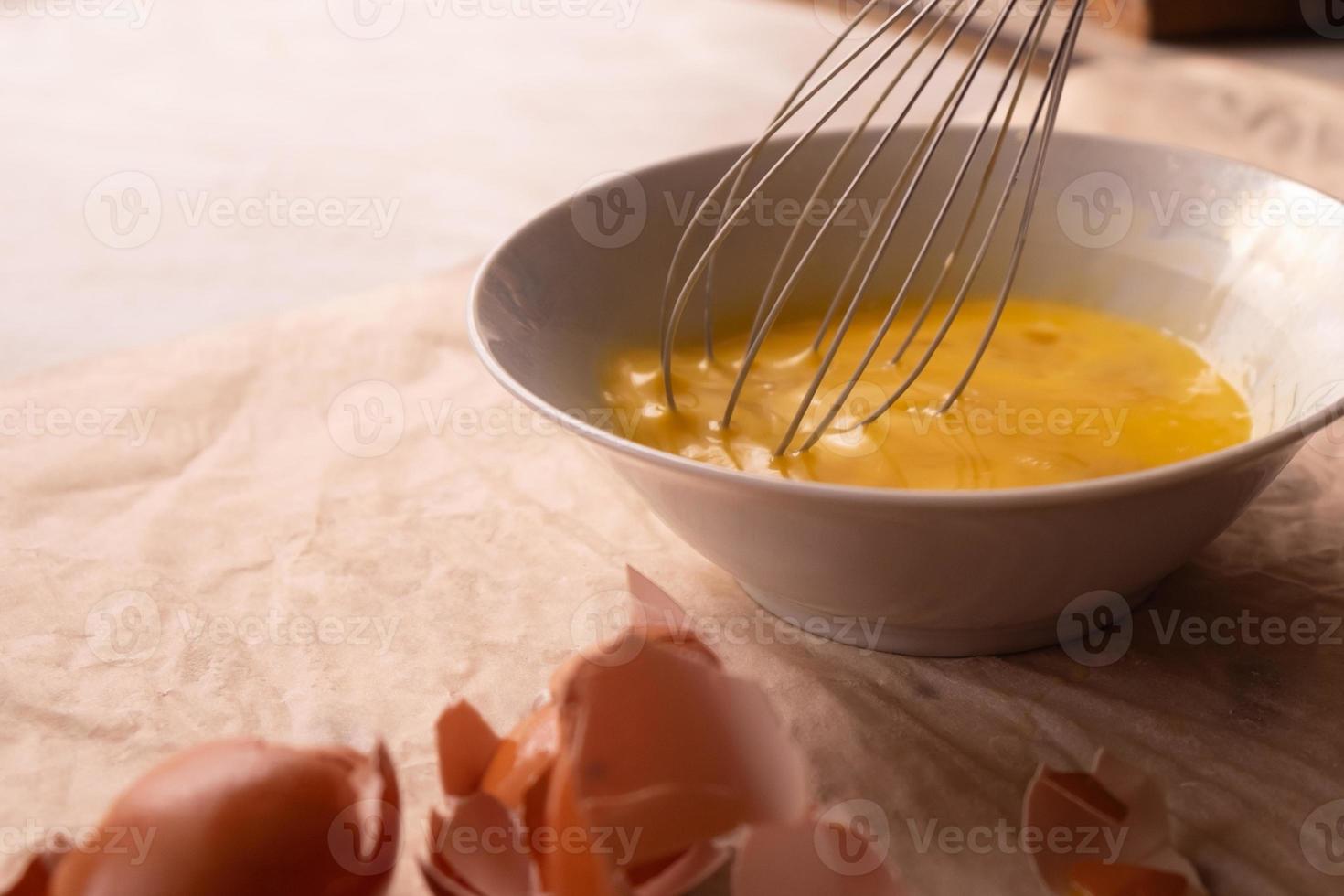 Beat eggs in a plate with a whisk photo