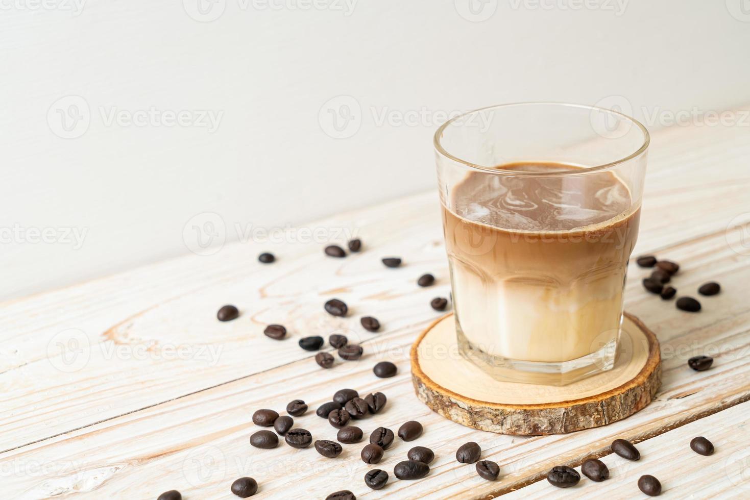 café sucio, leche fría cubierta con un chupito de café expreso caliente foto