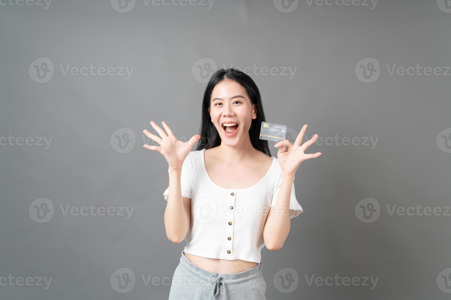 Mujer asiática con cara feliz y presentando tarjeta de crédito en mano mostrando confianza y seguridad para realizar el pago foto