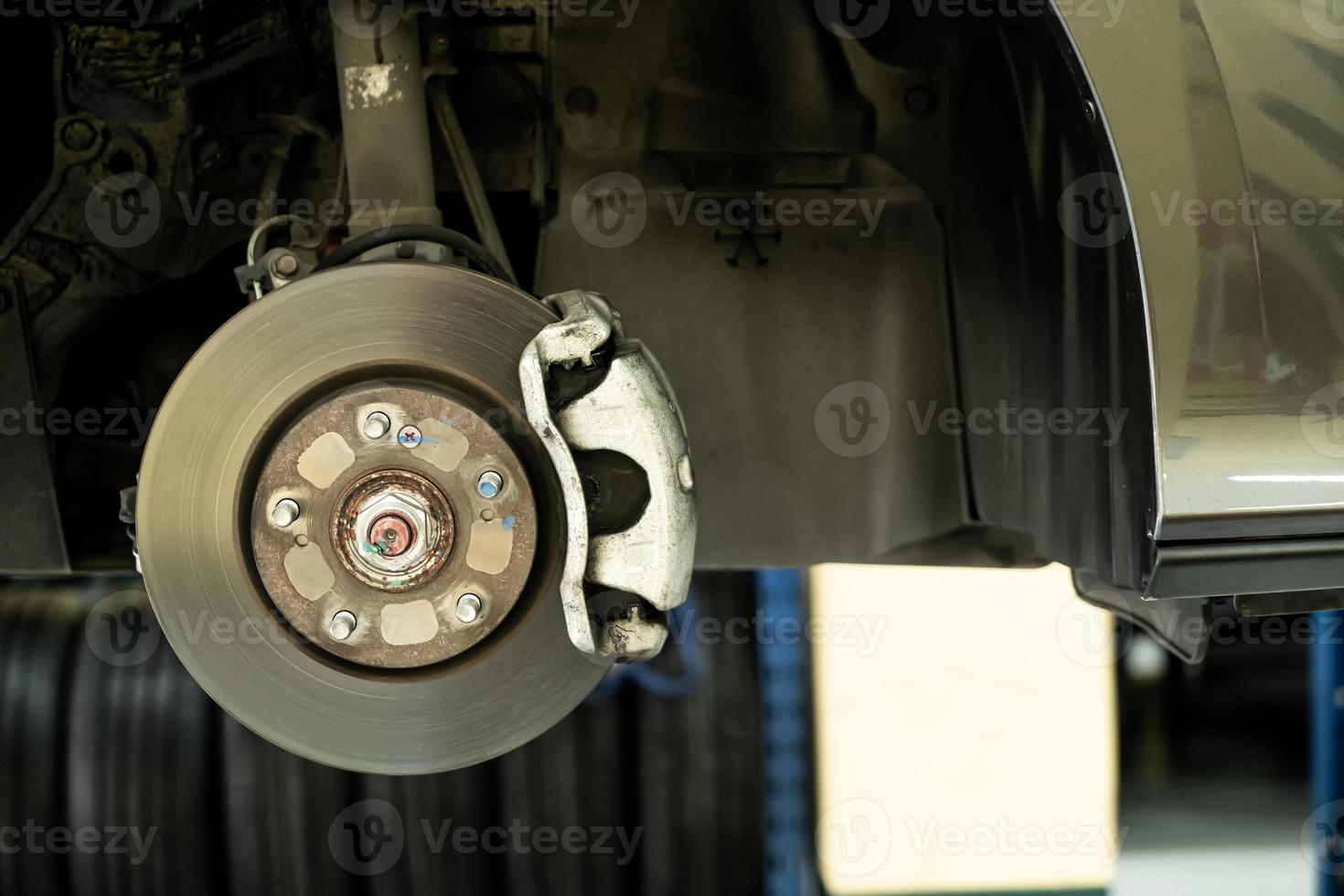 Disc car close up - mechanic unscrewing automobile parts while working under a lifted auto photo