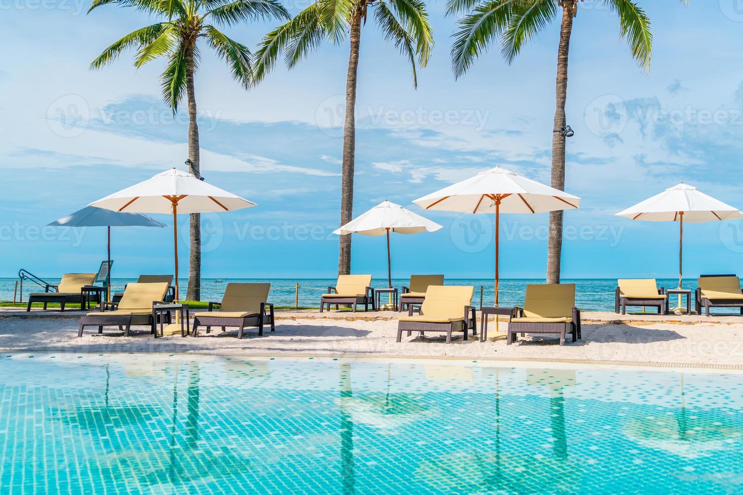 Beautiful tropical beach and sea with umbrella and chair around swimming pool in hotel resort photo