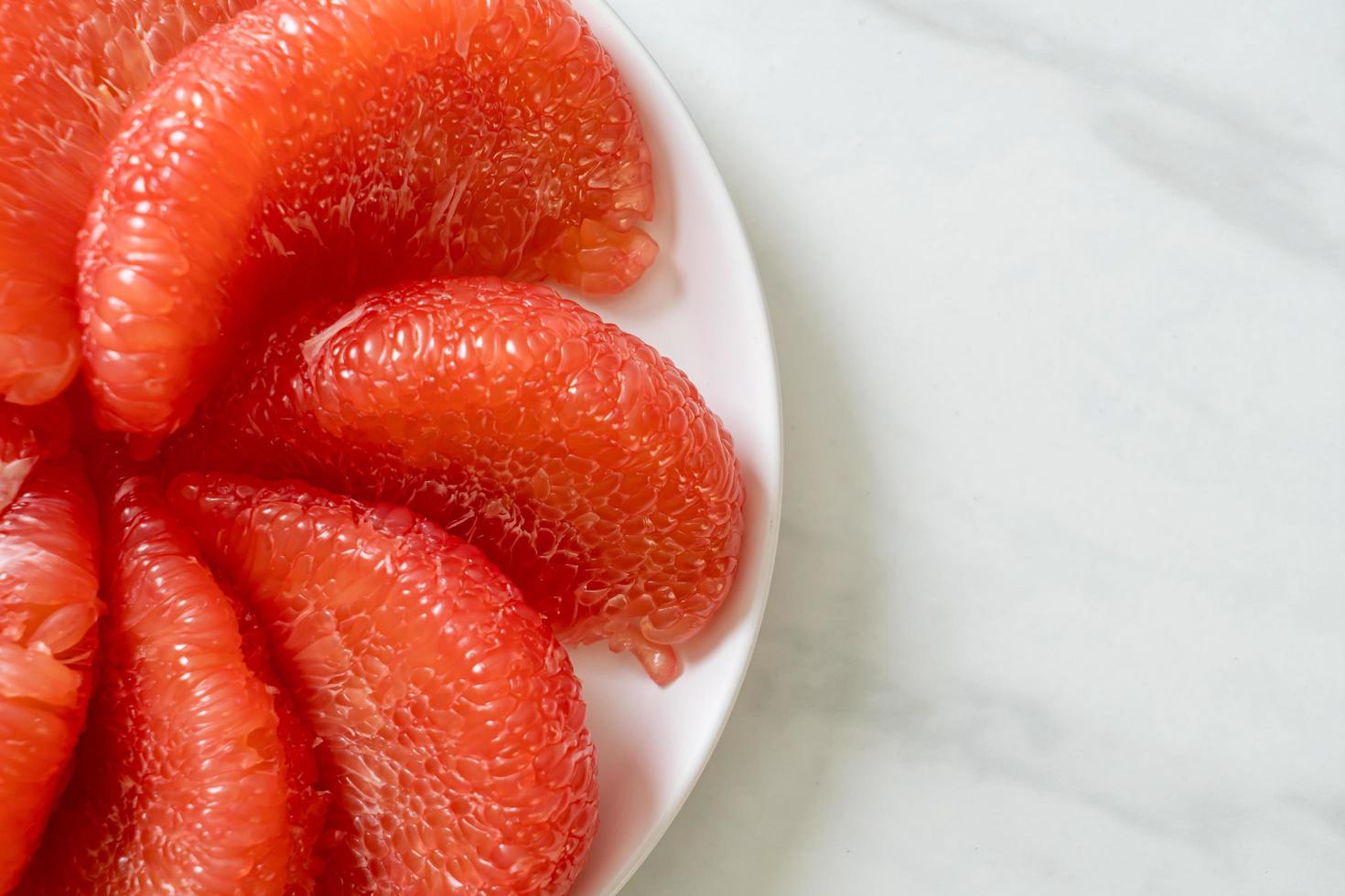 Fresh red pomelo fruit or grapefruit on plate photo