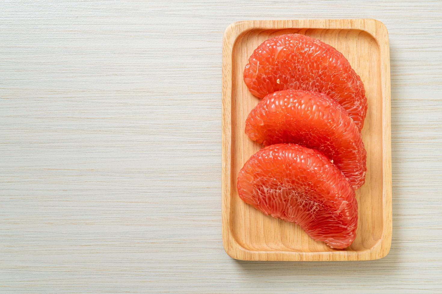 Fresh red pomelo fruit or grapefruit on plate photo