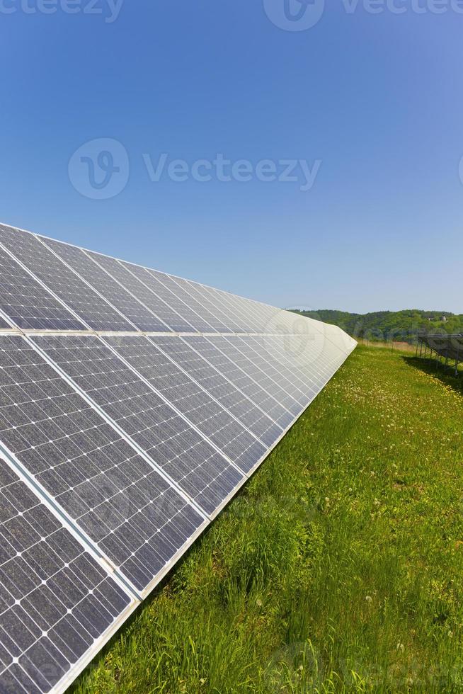 Estación de energía solar en la pradera de flores de verano foto