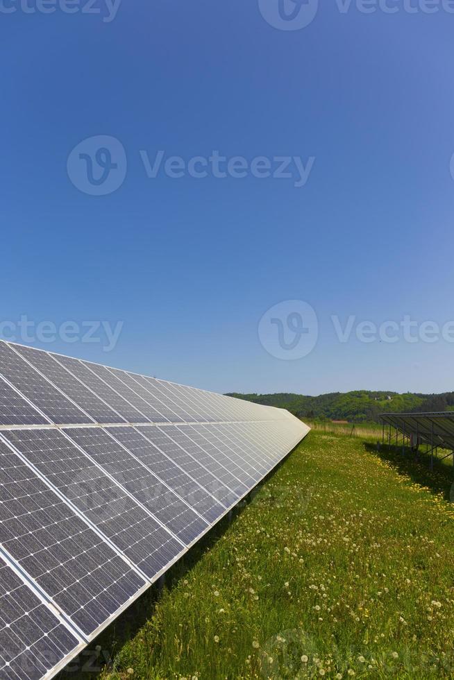 Estación de energía solar en la pradera de flores de verano foto