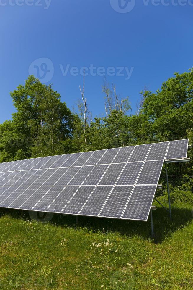 Estación de energía solar en la pradera de flores de verano foto