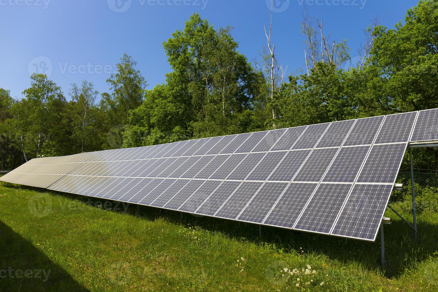 Estación de energía solar en la pradera de flores de verano foto