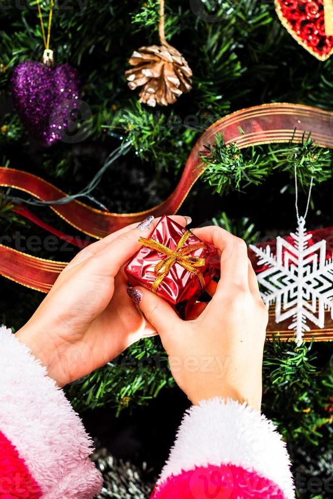 Hand holding Christmas ornament in front of Christmas tree photo