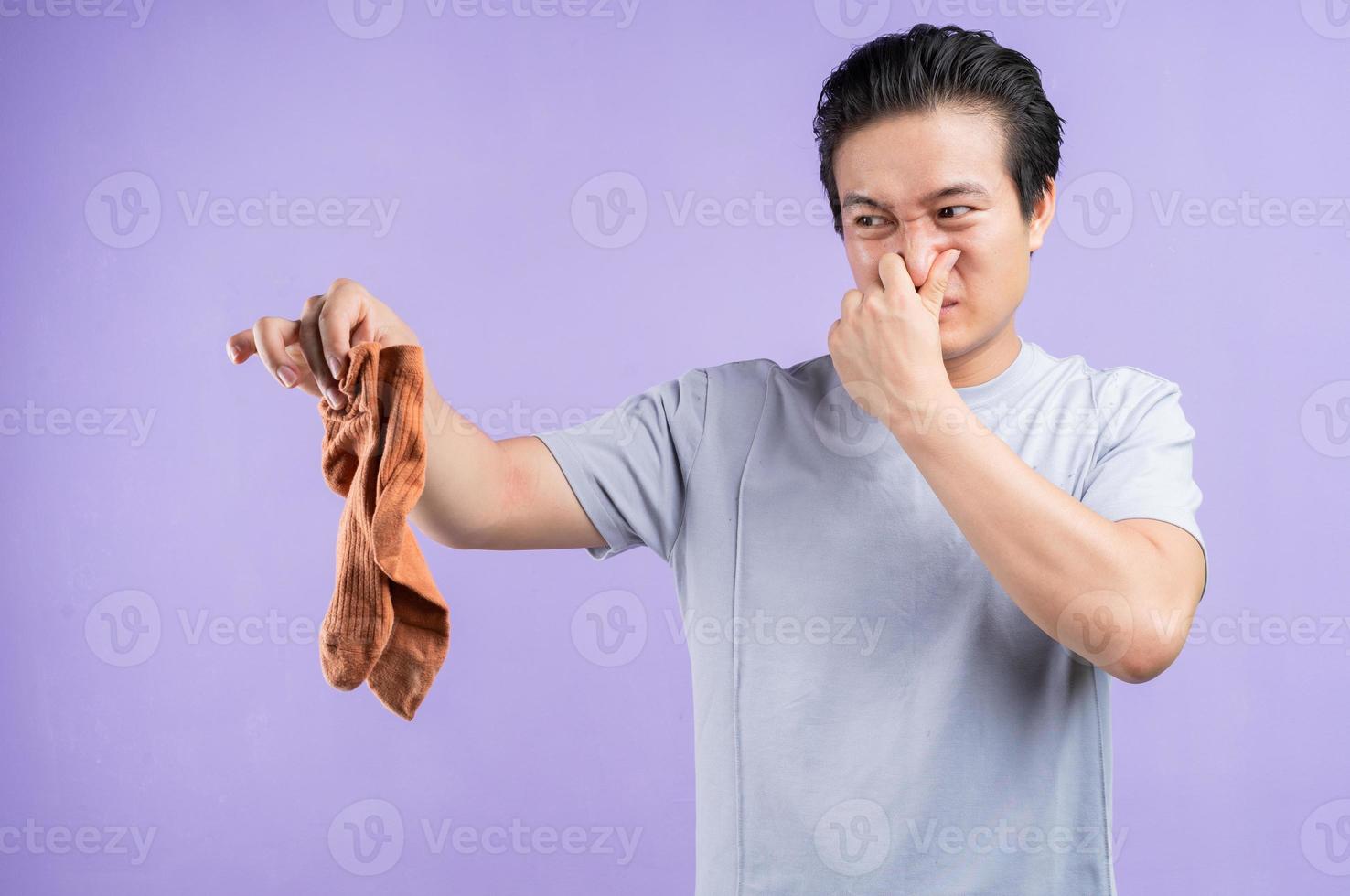 Hombre asiático sosteniendo calcetines sobre fondo púrpura foto