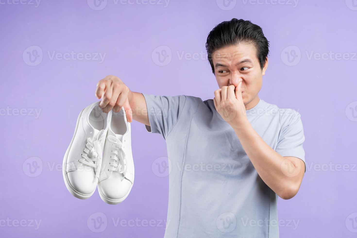 hombre asiático, tenencia, zapatillas de deporte, en, fondo púrpura foto